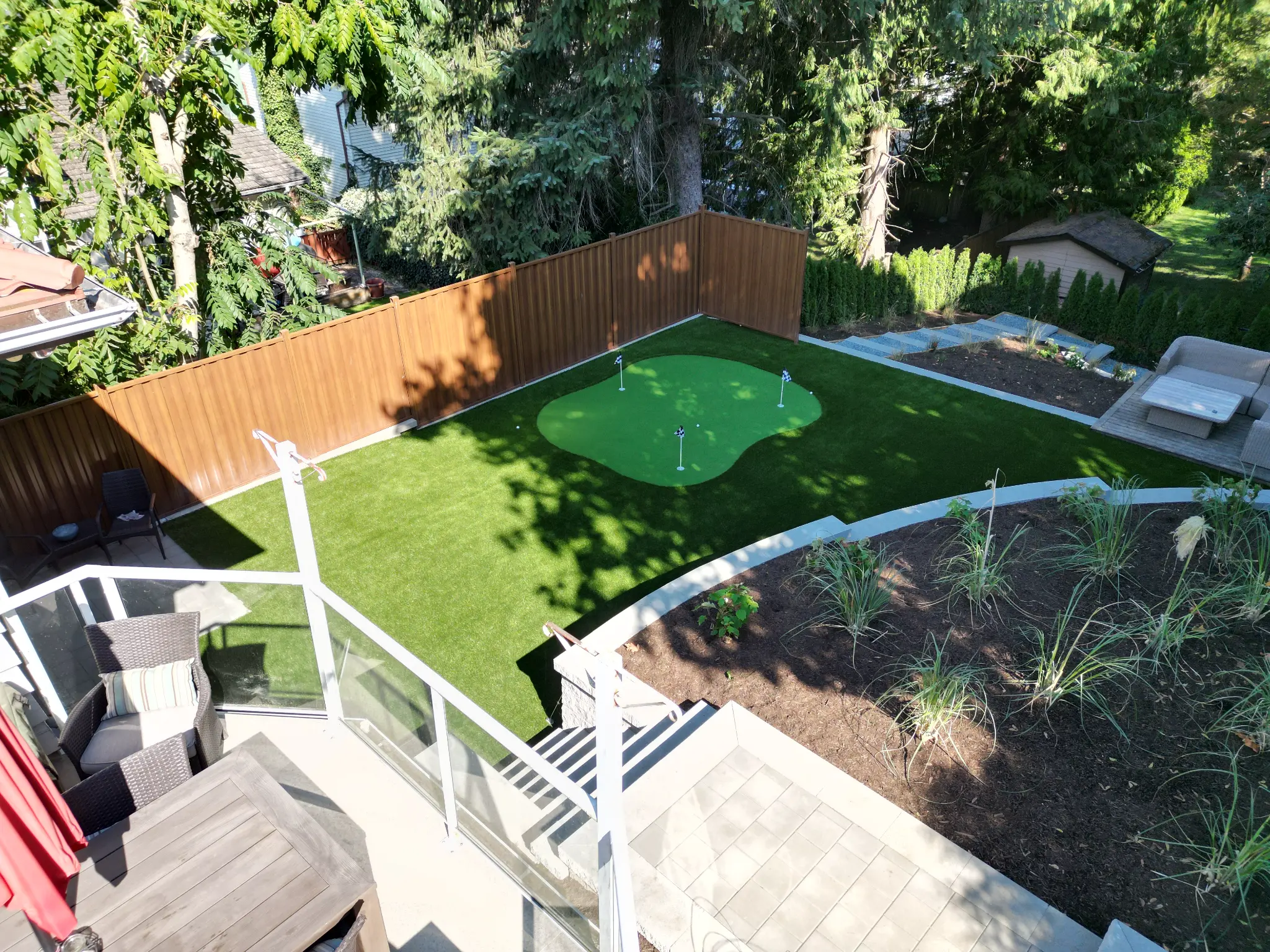Elevated view of the completed putting green, artificial turf, patio, and curved garden bed