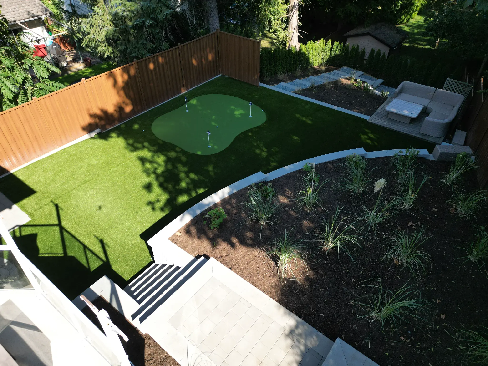 Wide view of the backyard putting green and low-maintenance artificial turf