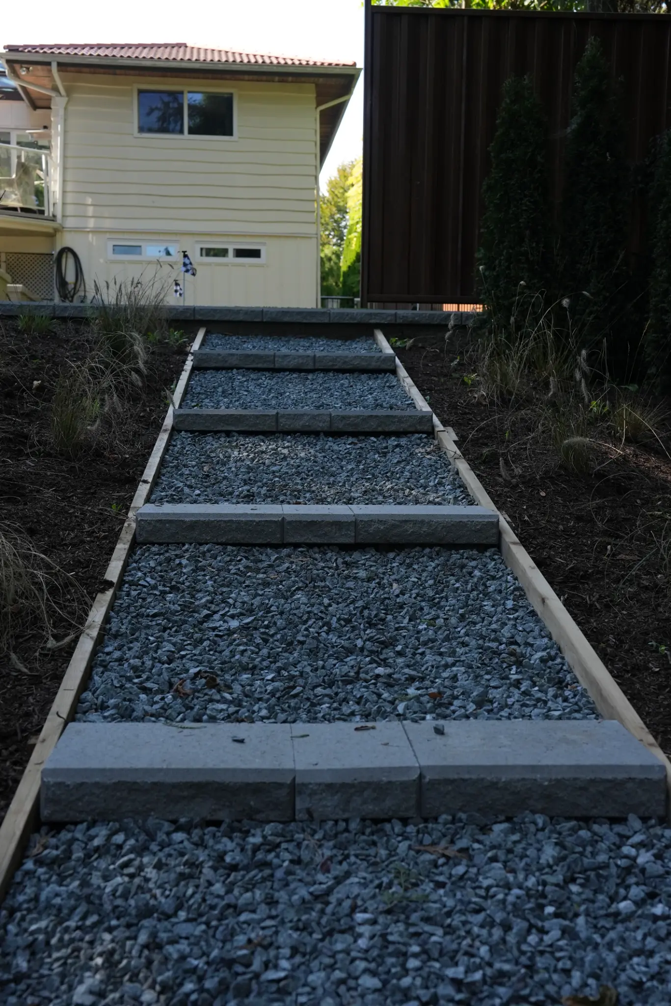 Gravel garden steps connecting the upper planting bed to the backyard