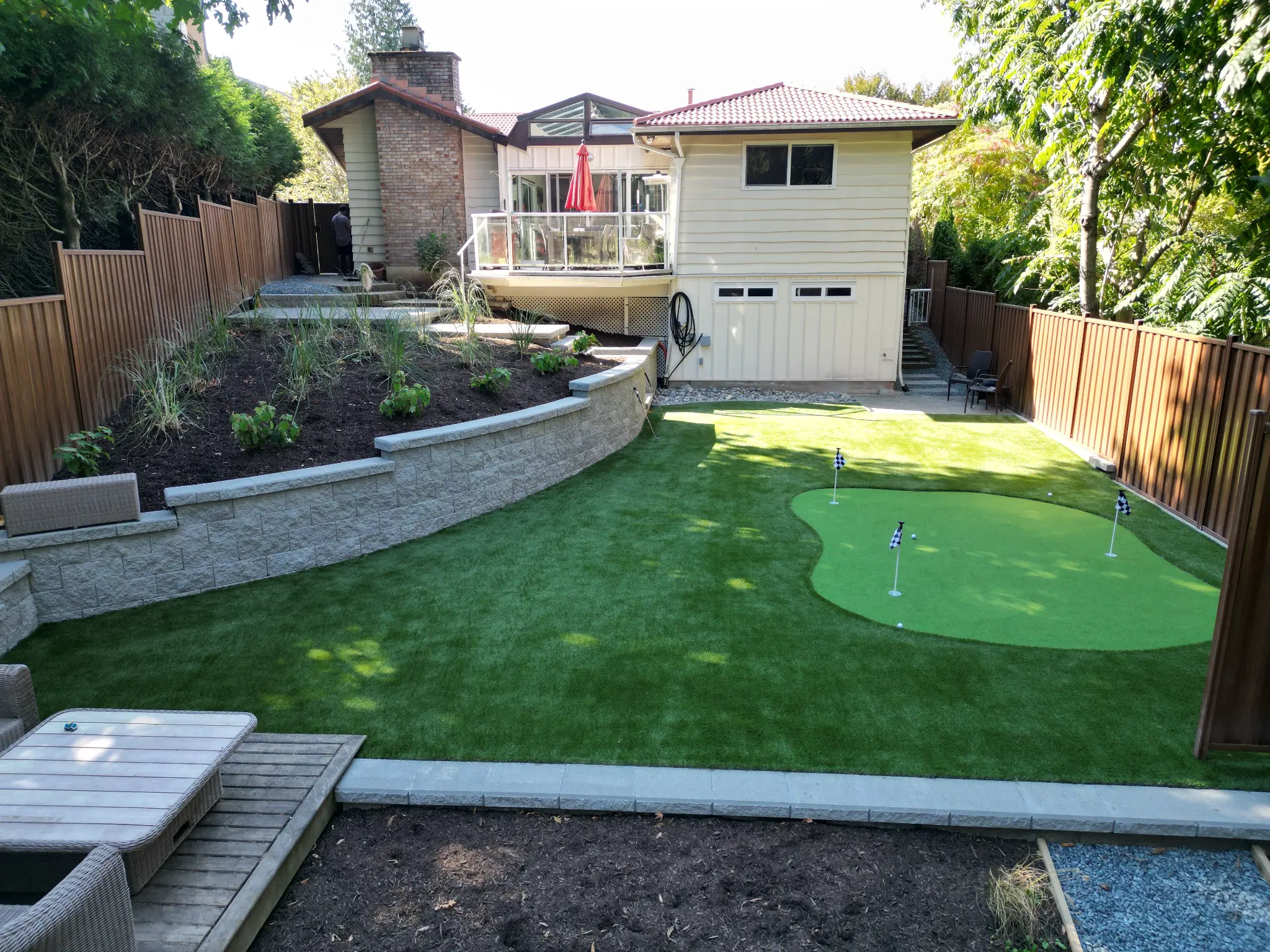 Completed Abbotsford backyard makeover with custom putting green, artificial turf, and retaining wall