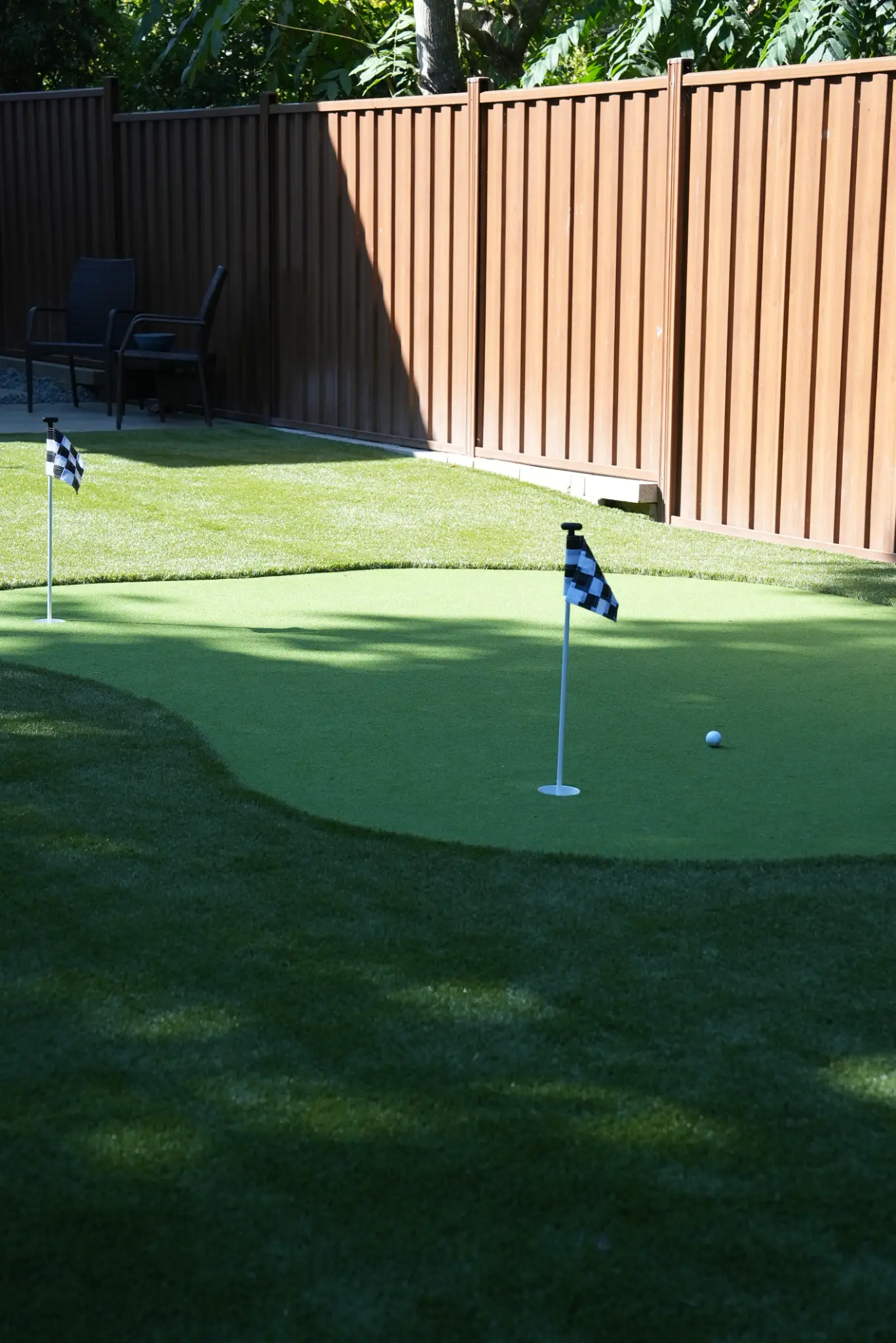 Putting surface detail with flags, fringe turf, and privacy fencing