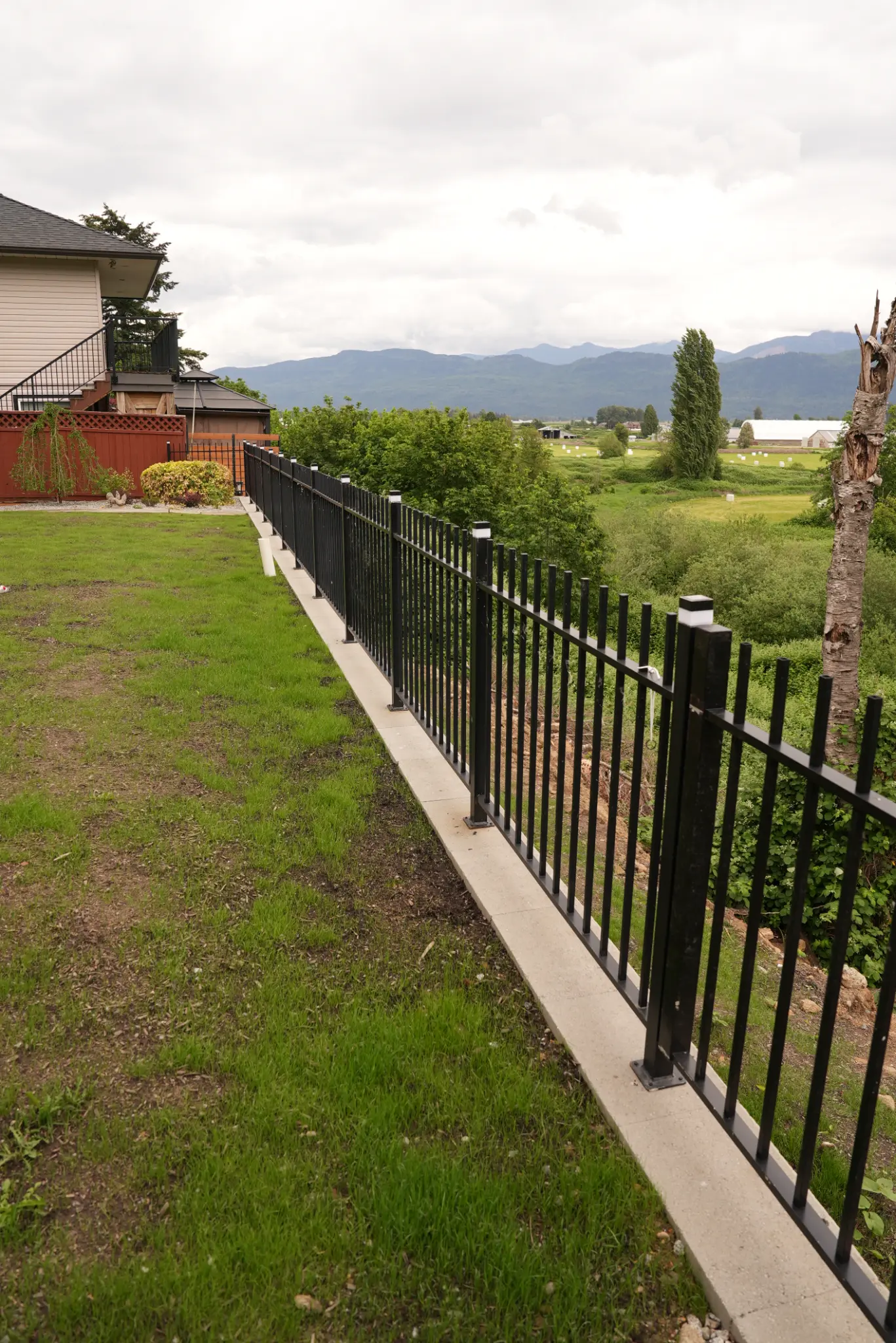 Finished concrete path, masonry work, and iron fence with mountain views