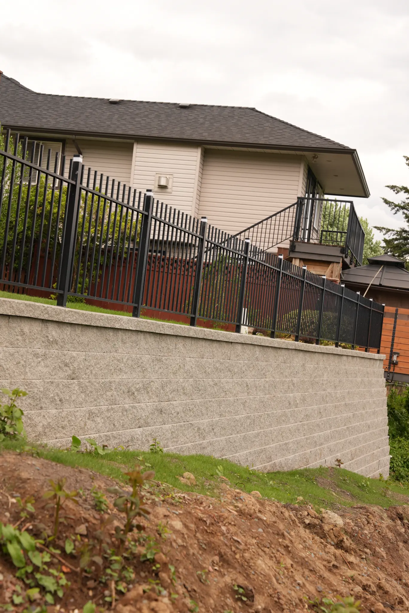 Retaining wall with fence and house in background
