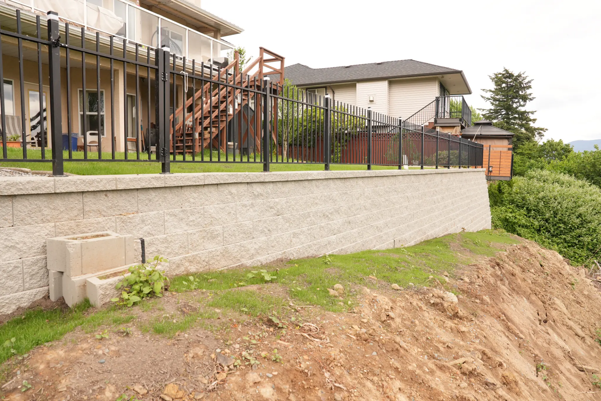 Front view of retaining wall with iron fencing and grading