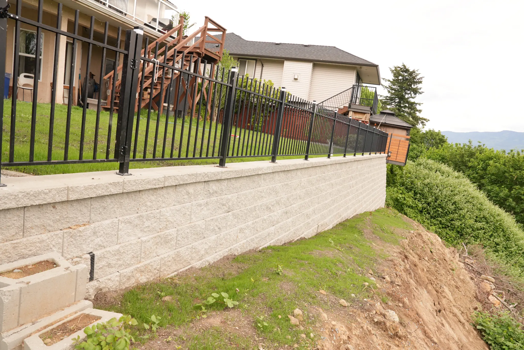 Side view of wall with fencing and house