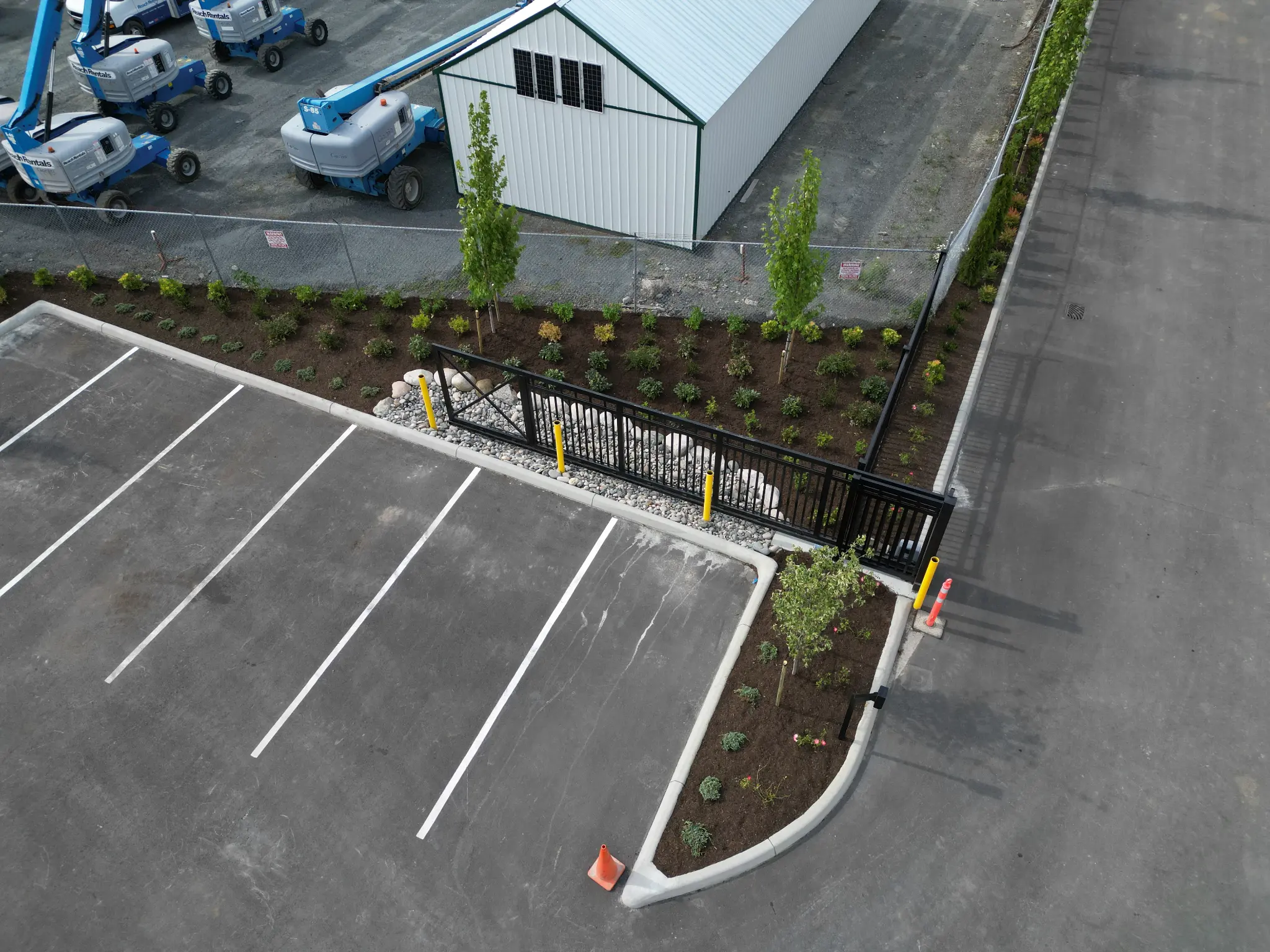 Commercial parking island with new trees, shrubs, decorative rock, and fencing
