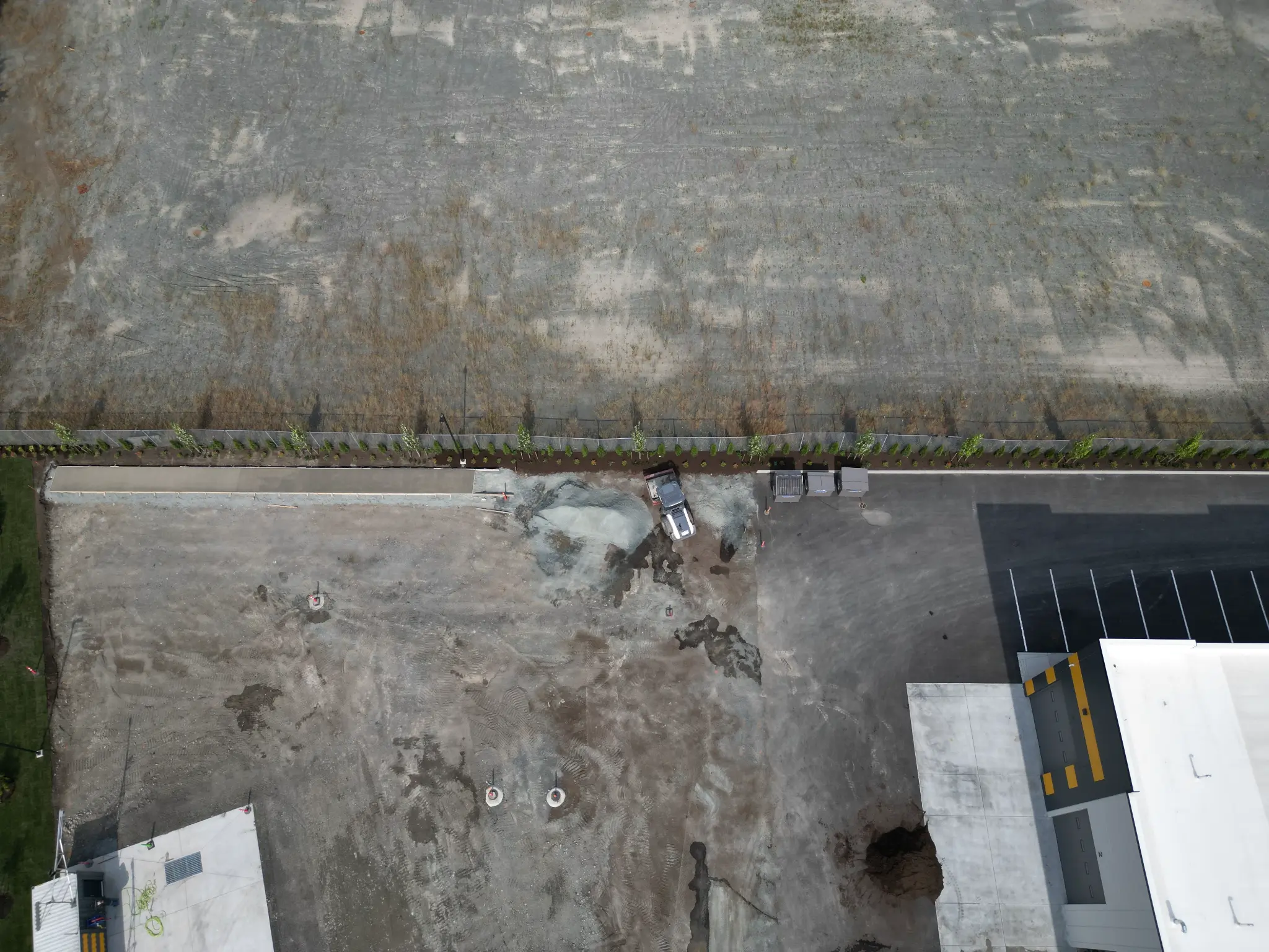 Early site-work aerial with grading and newly installed perimeter landscaping
