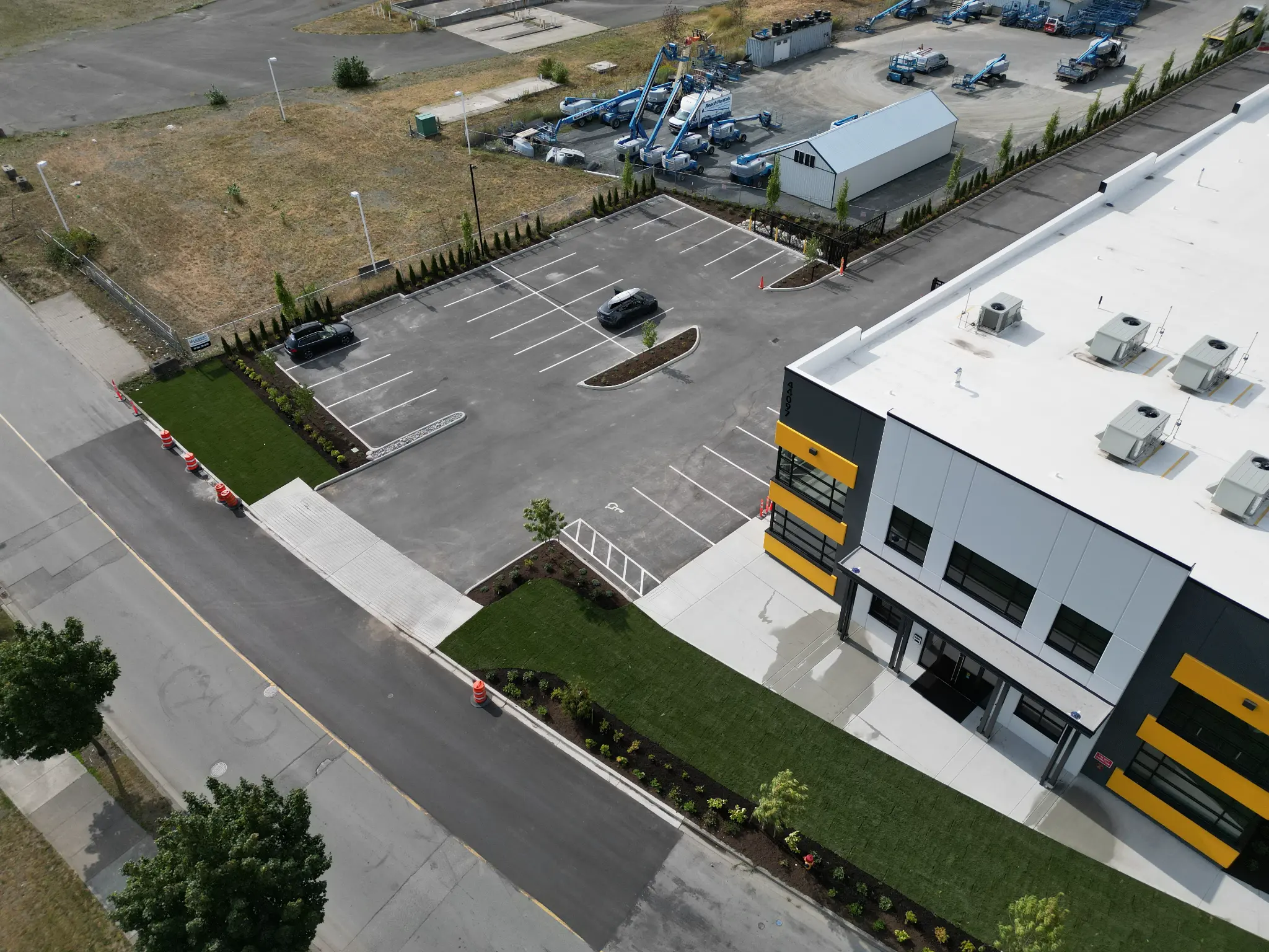 Angled aerial of the finished building, parking lot, lawn, and garden beds