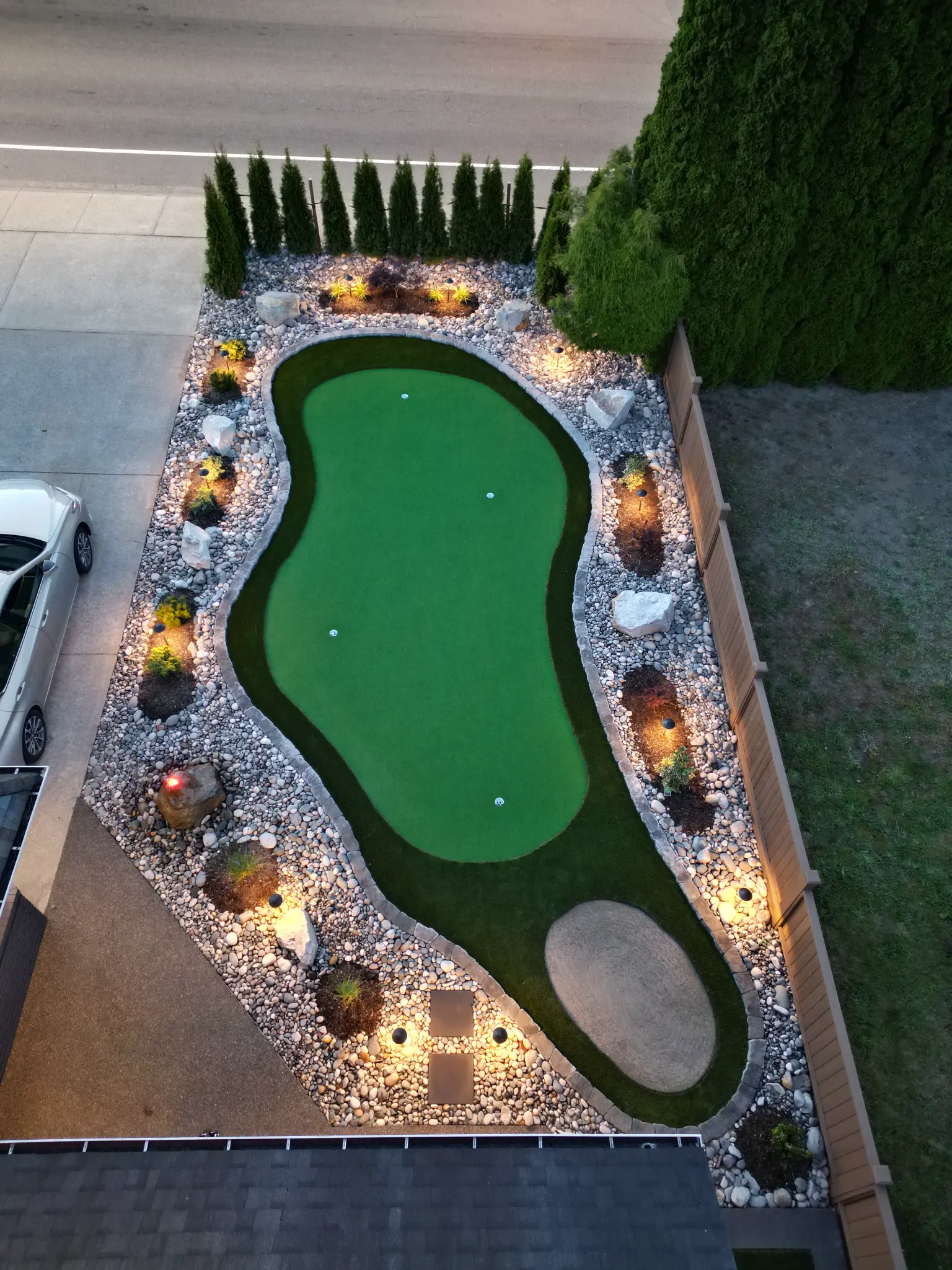 Custom putting green with landscape lighting and rock borders