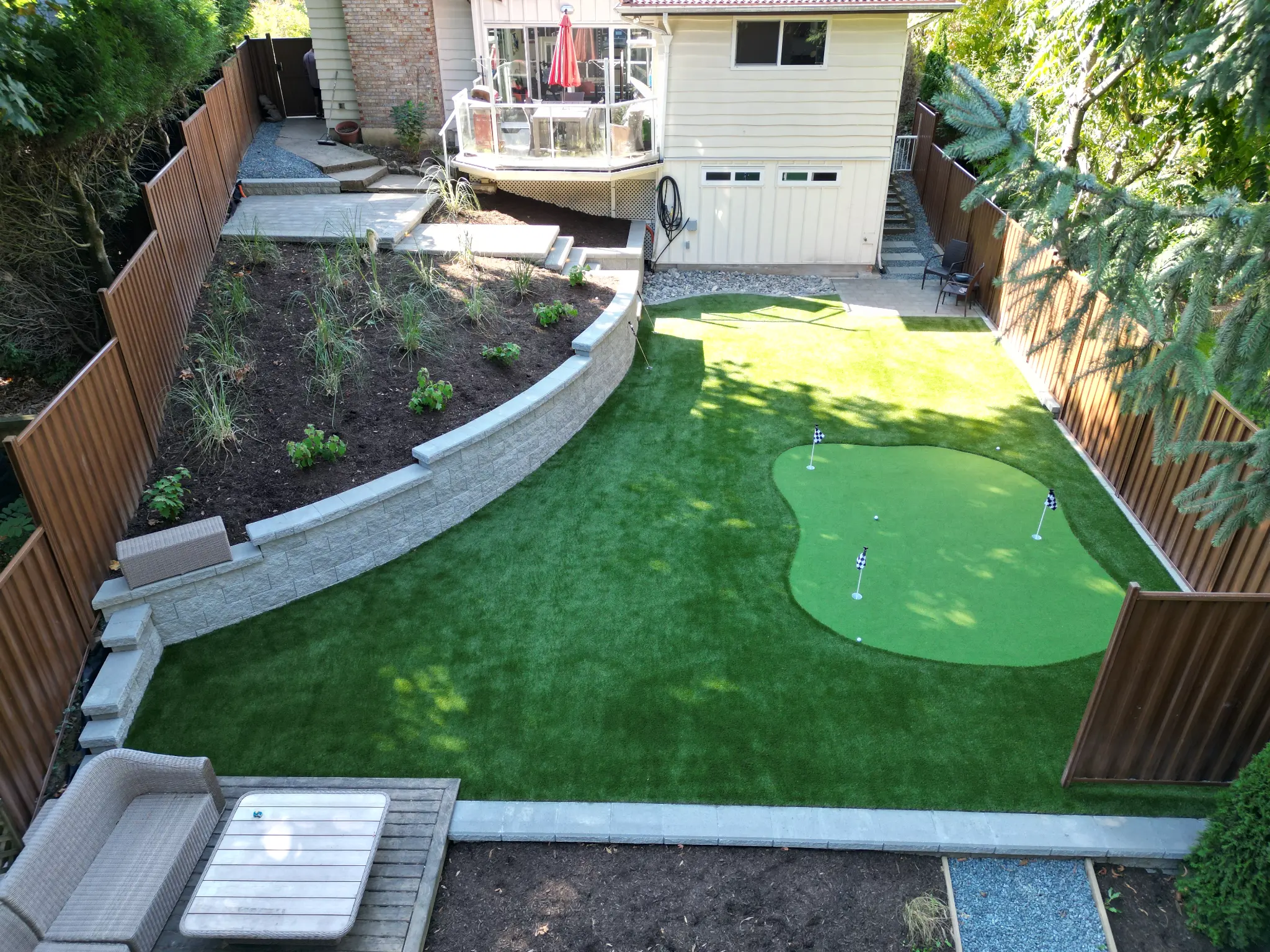 Backyard with artificial turf, putting green, and retaining walls