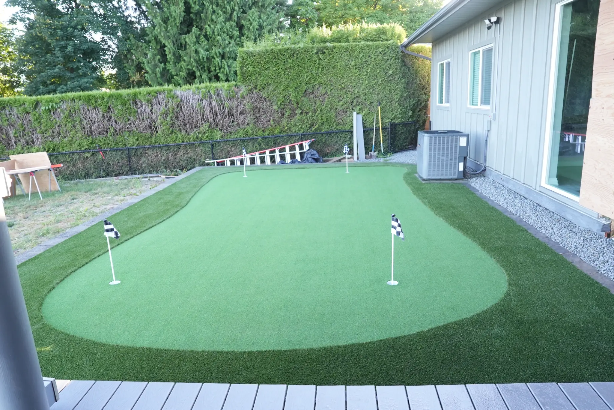 Artificial turf and putting surface framed by a curved retaining wall