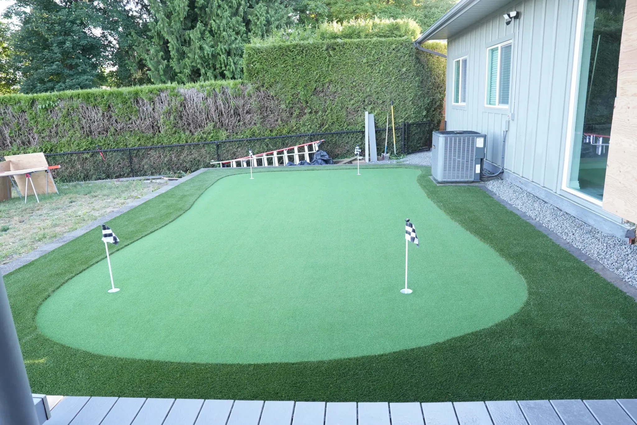 Close view of the putting green, fringe turf, and structural wall