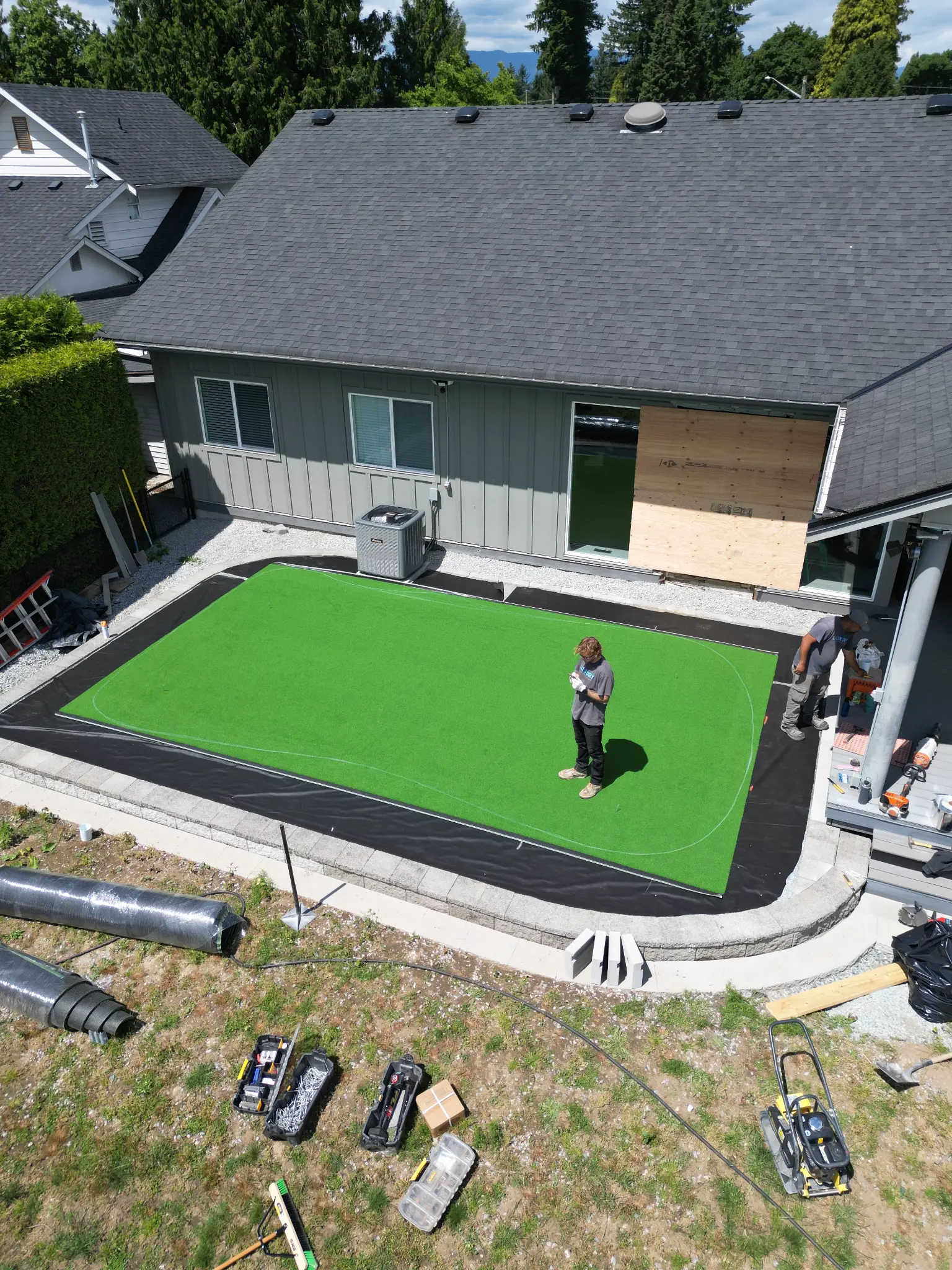 Wide aerial view of the backyard transformation and retaining-wall layout