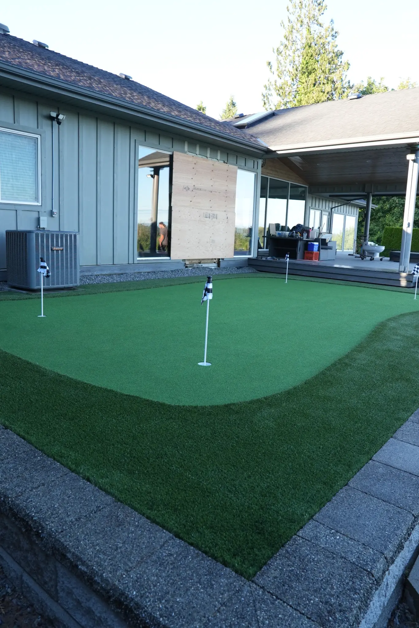 Ground-level putting green view with retaining wall and landscape lighting