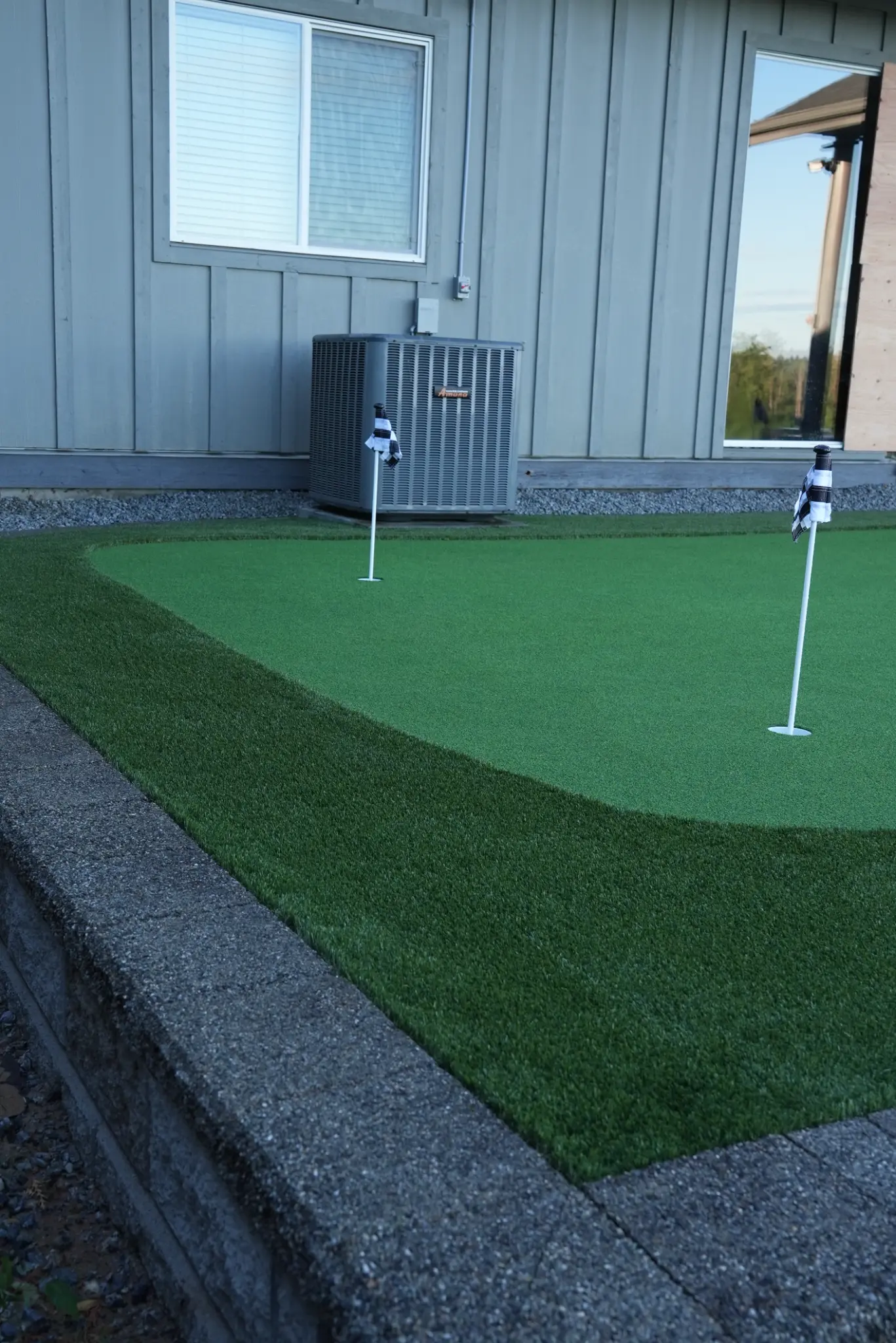 Close ground-level view of the putting green and retaining-wall finish