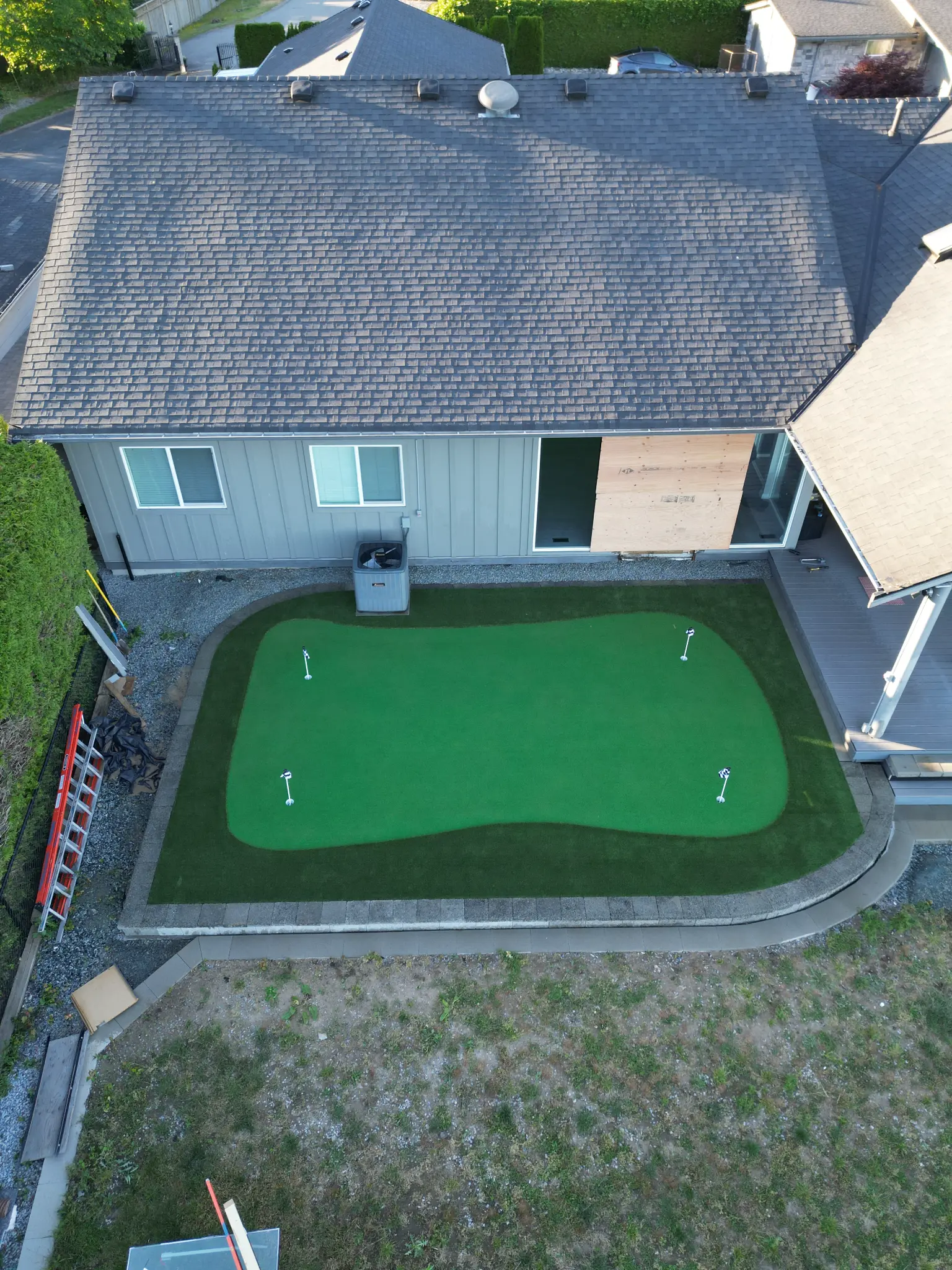 Wide aerial view of the Maple Ridge putting green, retaining walls, and artificial turf