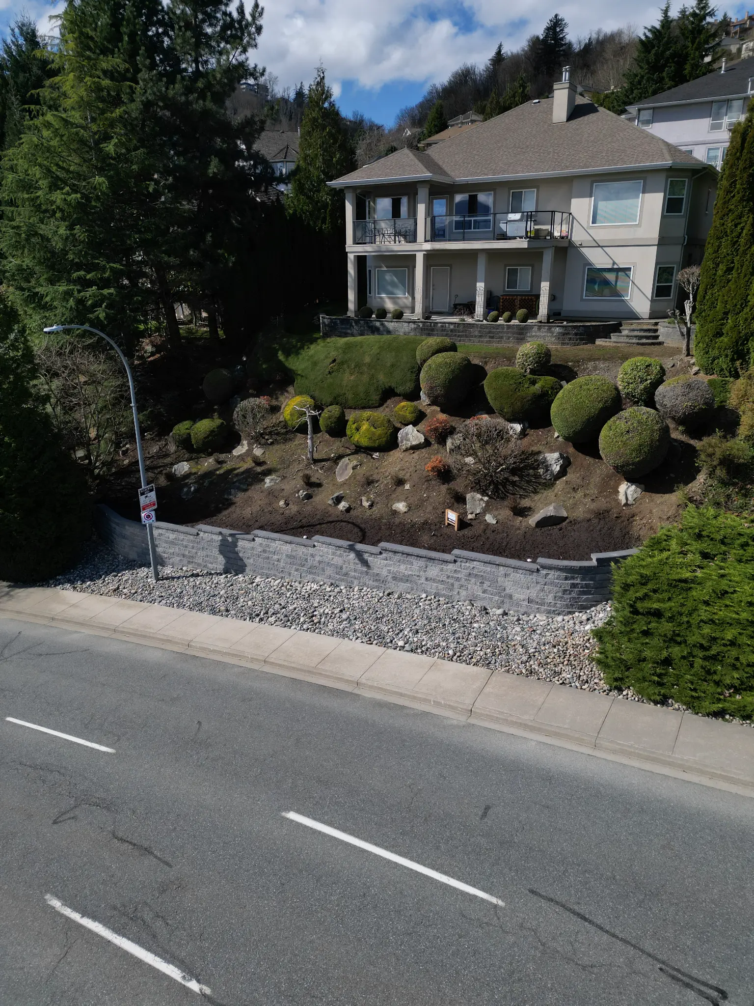 Daytime aerial of retaining wall with house and landscaped slope