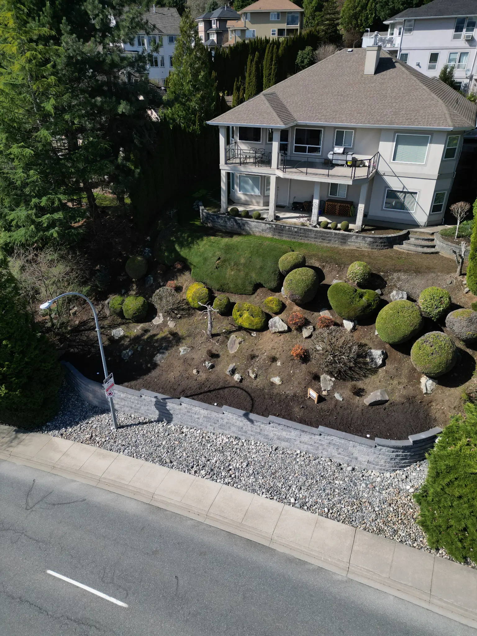 Aerial drone view of retaining wall with property and topiary shrubs