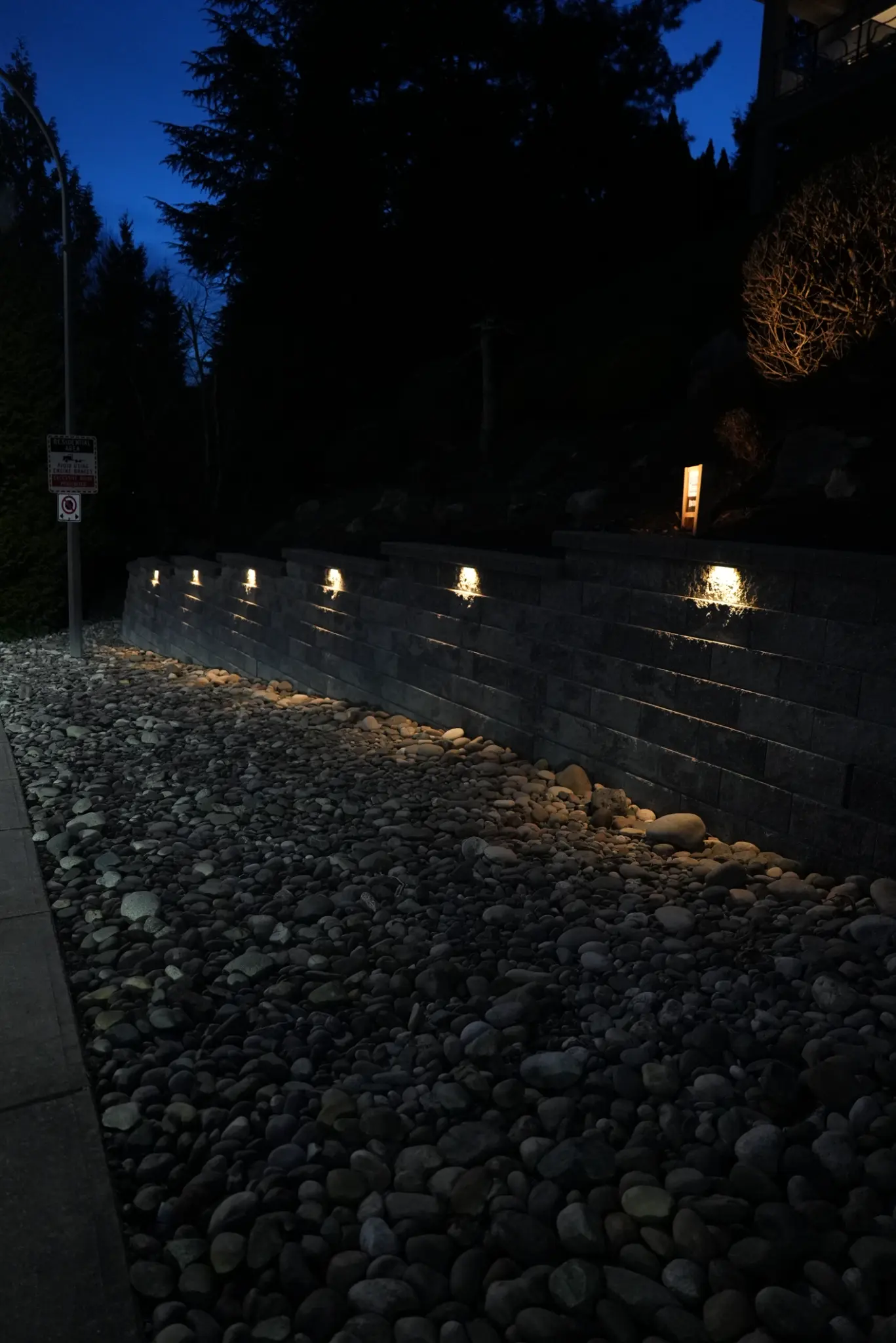 Retaining wall at dusk with river rock base and warm lighting