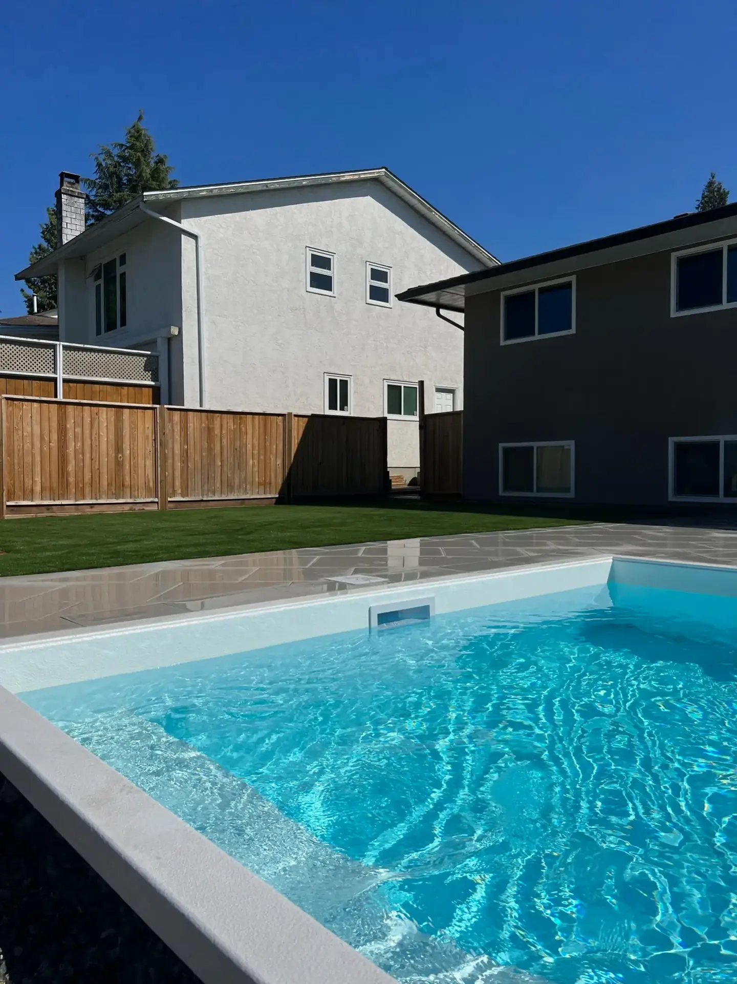 Completed backyard pool with artificial turf and stone patio